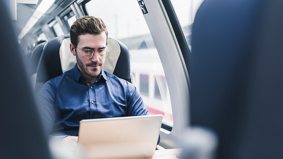 Mann arbeitet unterwegs mit Laptop